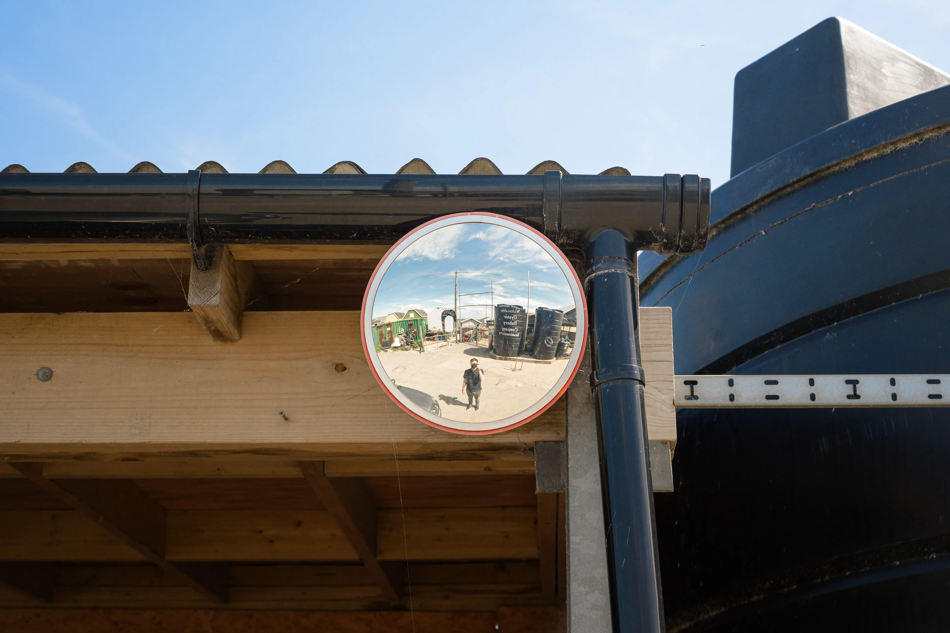 Nick Harris reflected in a convex mirror beside beach huts