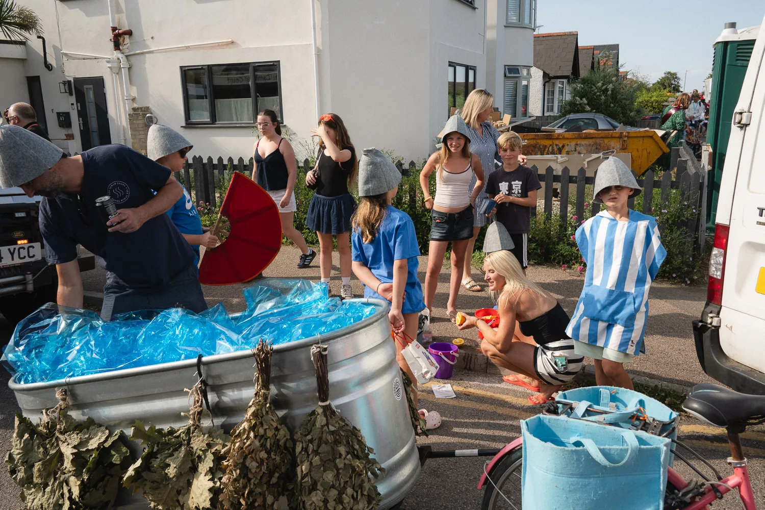 People gathered around a blue paddling pool on a street